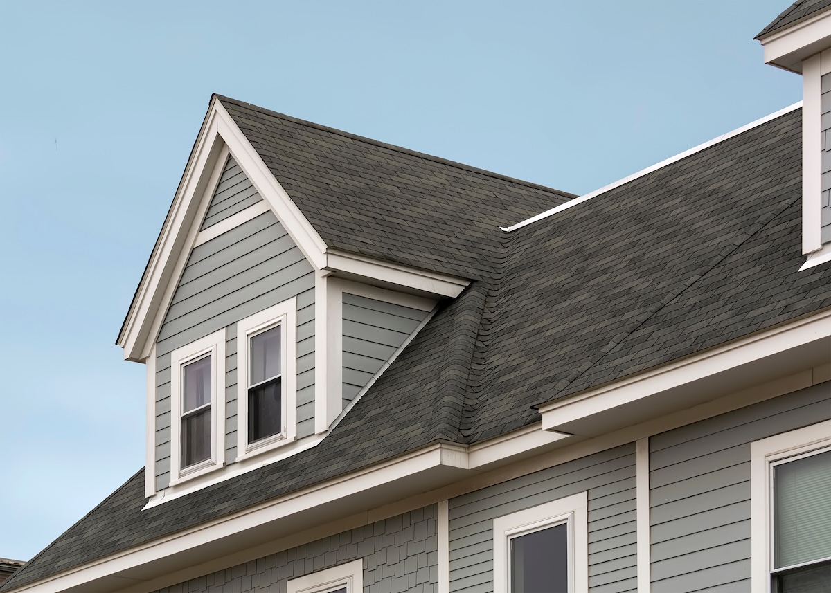 metal roof vs shingles Detailed view of a gable-style dormer window on a sloped roof of a newly built family house 
