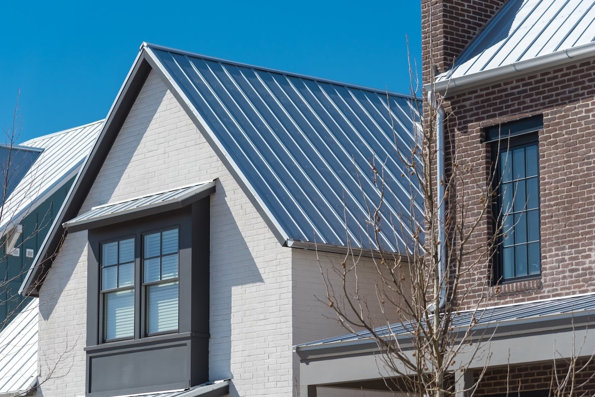Close-up second floor of brand new house with metal roof and covered gutter near Oklahoma City, US. Modern two story townhouse with bay windows and thin brick siding sunny winter day blue sky