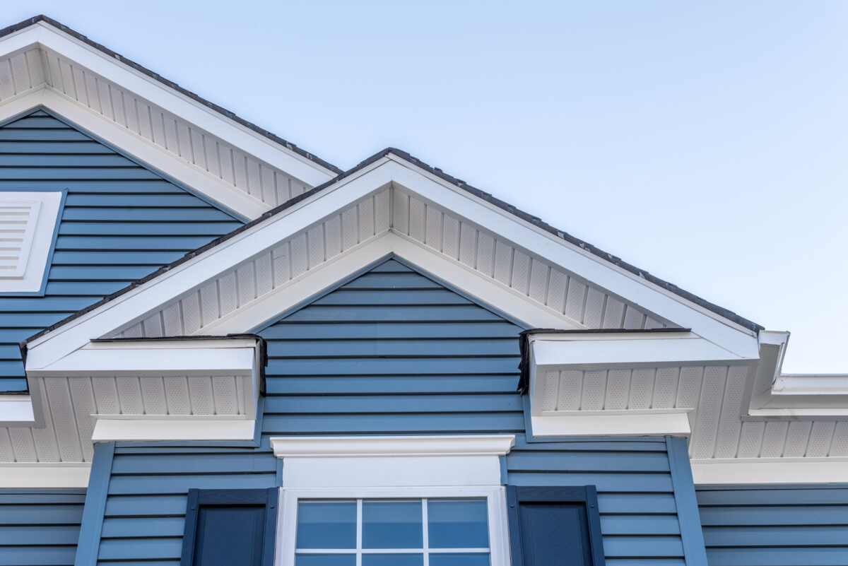 Cloudy sky reflecting on a newly installed window with dark brown aluminum frame and grills on an American single family house roof fascia replacement cost
