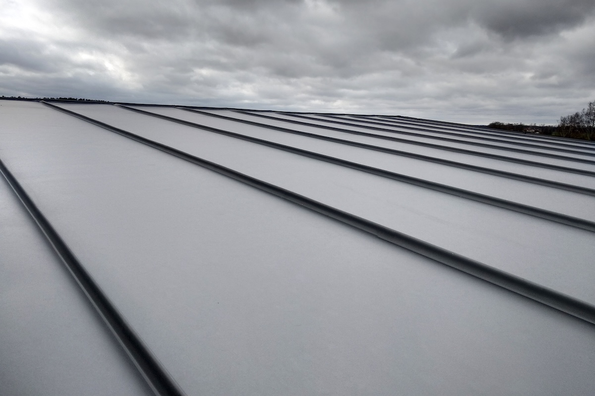 Close-up detail of house roof made from gray metal sheets. standing seam vs corrugated metal roof