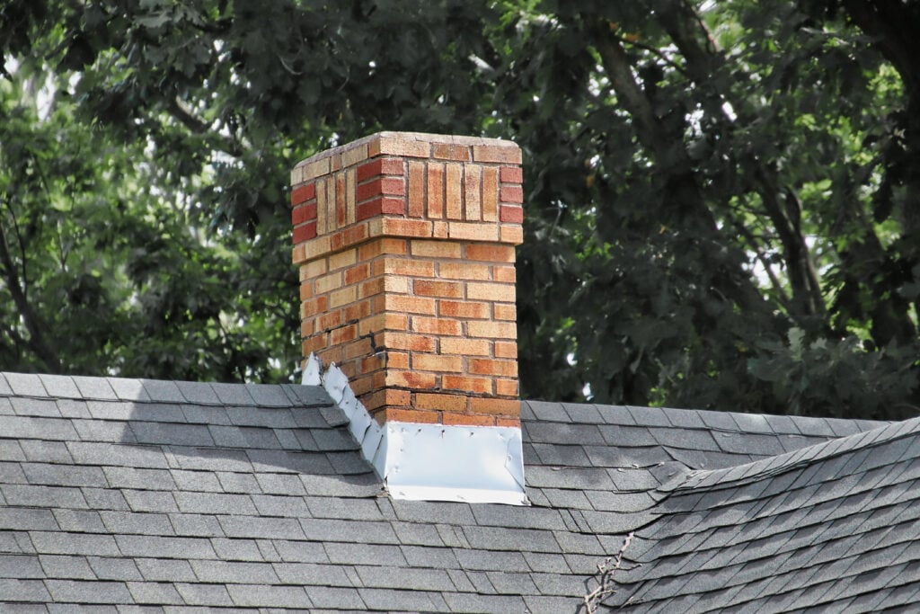 An old chimney on a shingles rooftop.