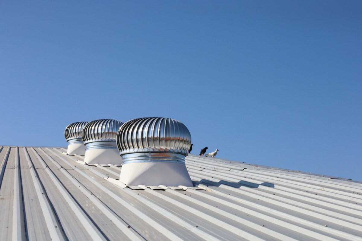 roof vent installation Ventilation fan on the roof. Three shiny metal rotating balls on industrial factory roof for circulating cool air into warehouse on blue sky background with selective focus.