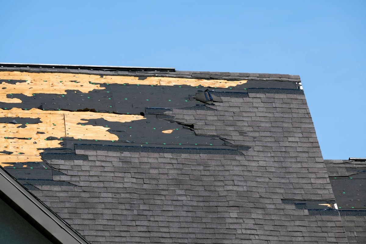 Damaged house roof with missing shingles