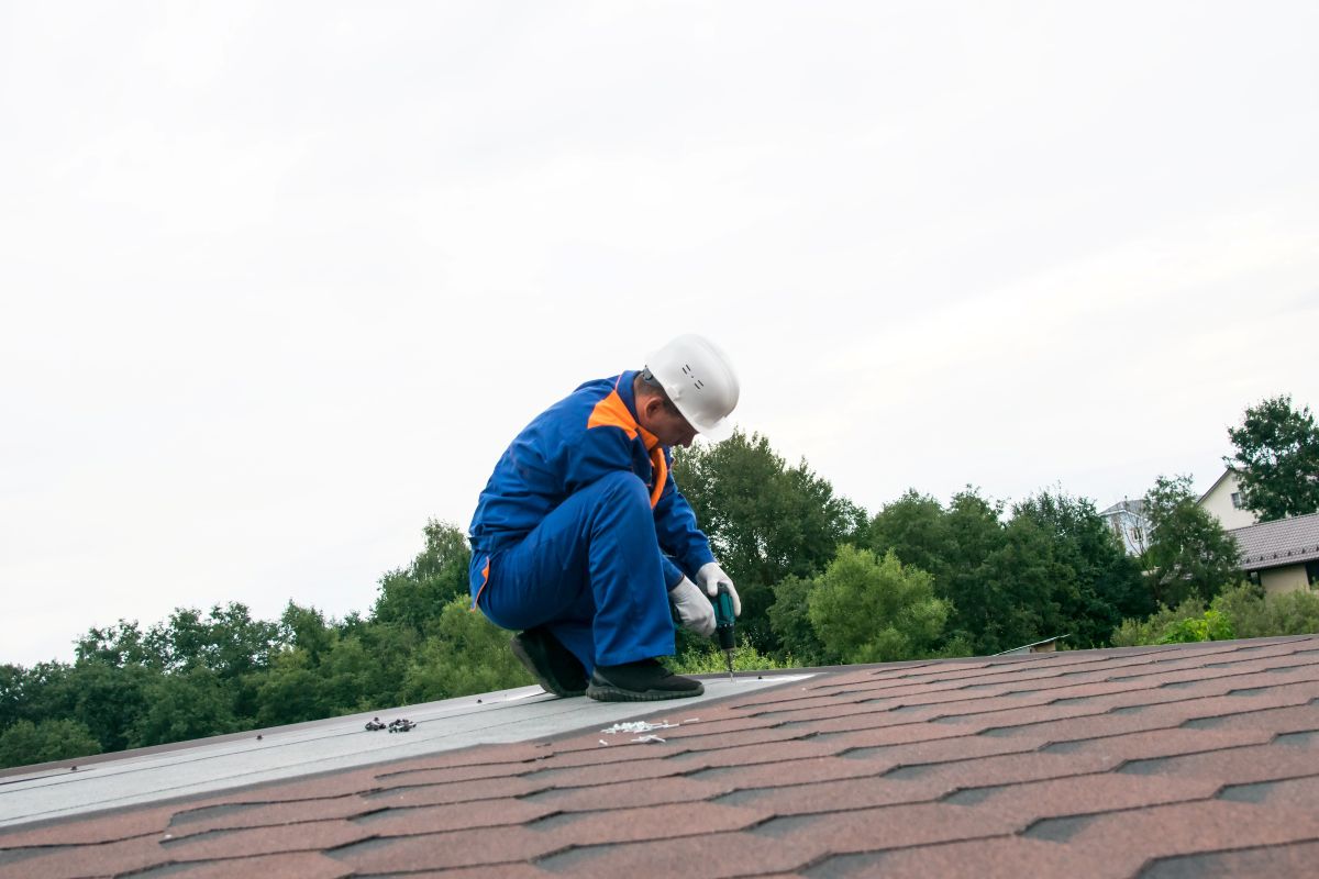 built up roofing worker installing shingles