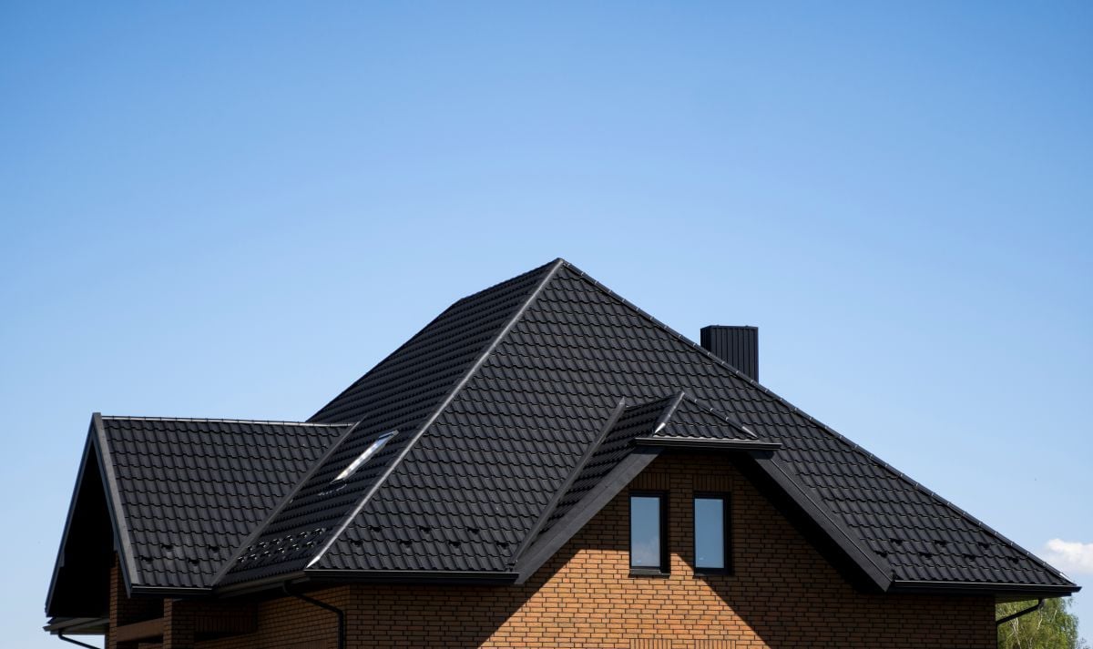 Brown corrugated metal profile roof installed on a modern house with attic windows