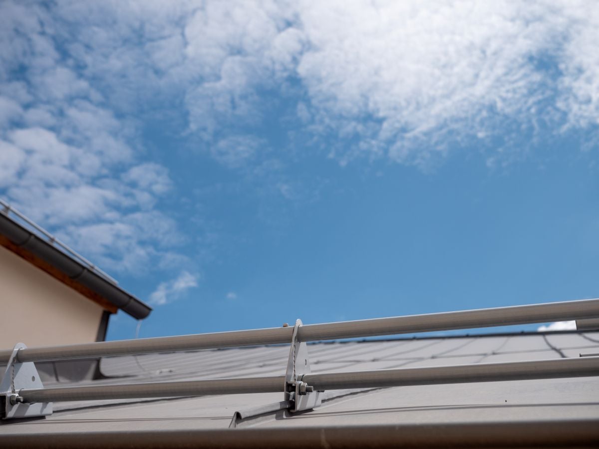 Metal snow guards on a standing seam roof under blue sky