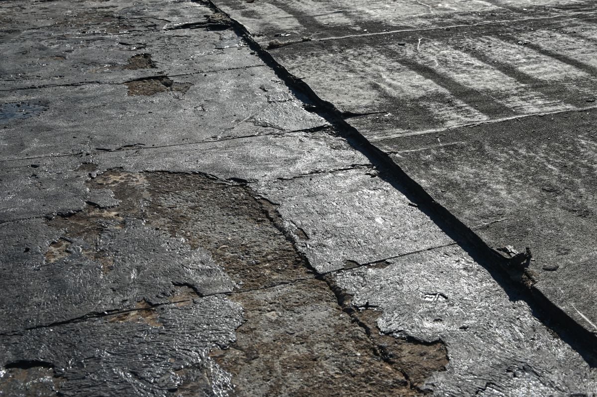 Bitumen flat roofing renovation, background texture of removed damaged insulation layer of roof
